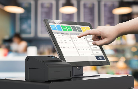 Picture of a hand with finger pointed out touching a point of sale touch screen device with a printer next to it.